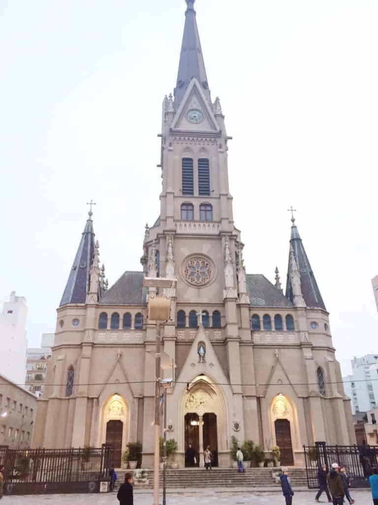 Gothic-style church with tall central spire, arched doorways, and people standing in front—a must-see highlight featured in many Argentina travel guide recommendations.