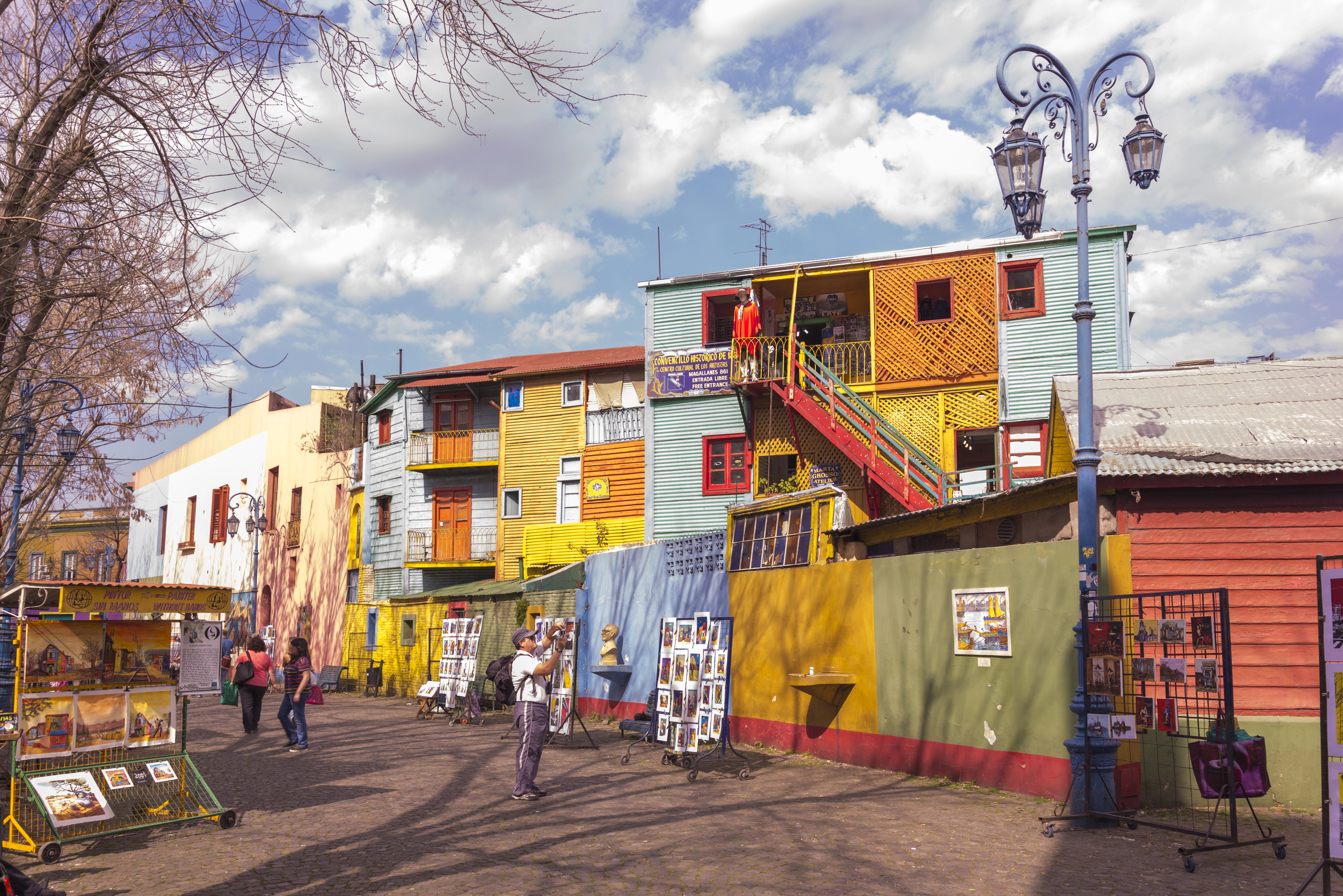 Colorful buildings and street art brighten a lively outdoor market scene, where people stroll, shop, and discover unique things to do in Buenos Aires.