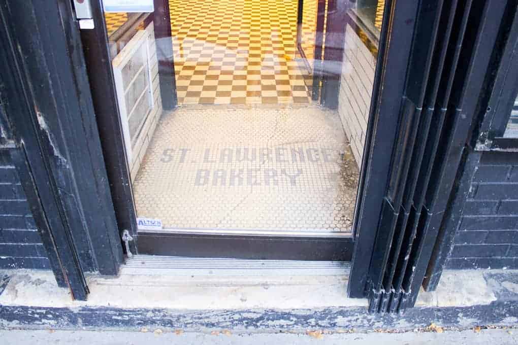 Bakery entrance with "St. Lawrence Bakery" written on white tile floor, checkered floor inside—a must-see spot on the Fletcher Beyond the Bagel Tour.