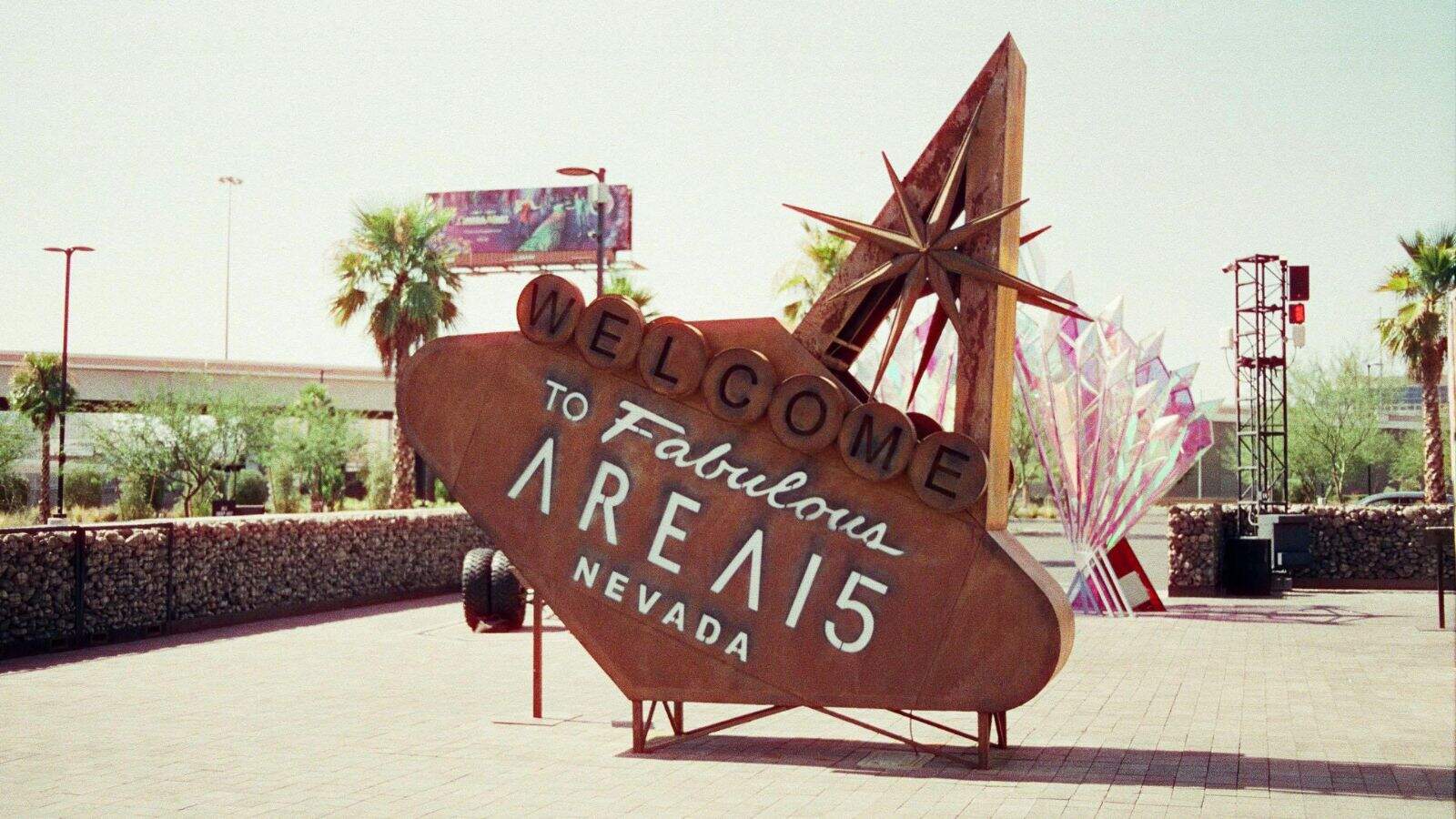 A large metal sign reads "Welcome to Fabulous Area 15 Nevada" in stylized text, resembling the famous Las Vegas sign, with palm trees and structures visible in the background.