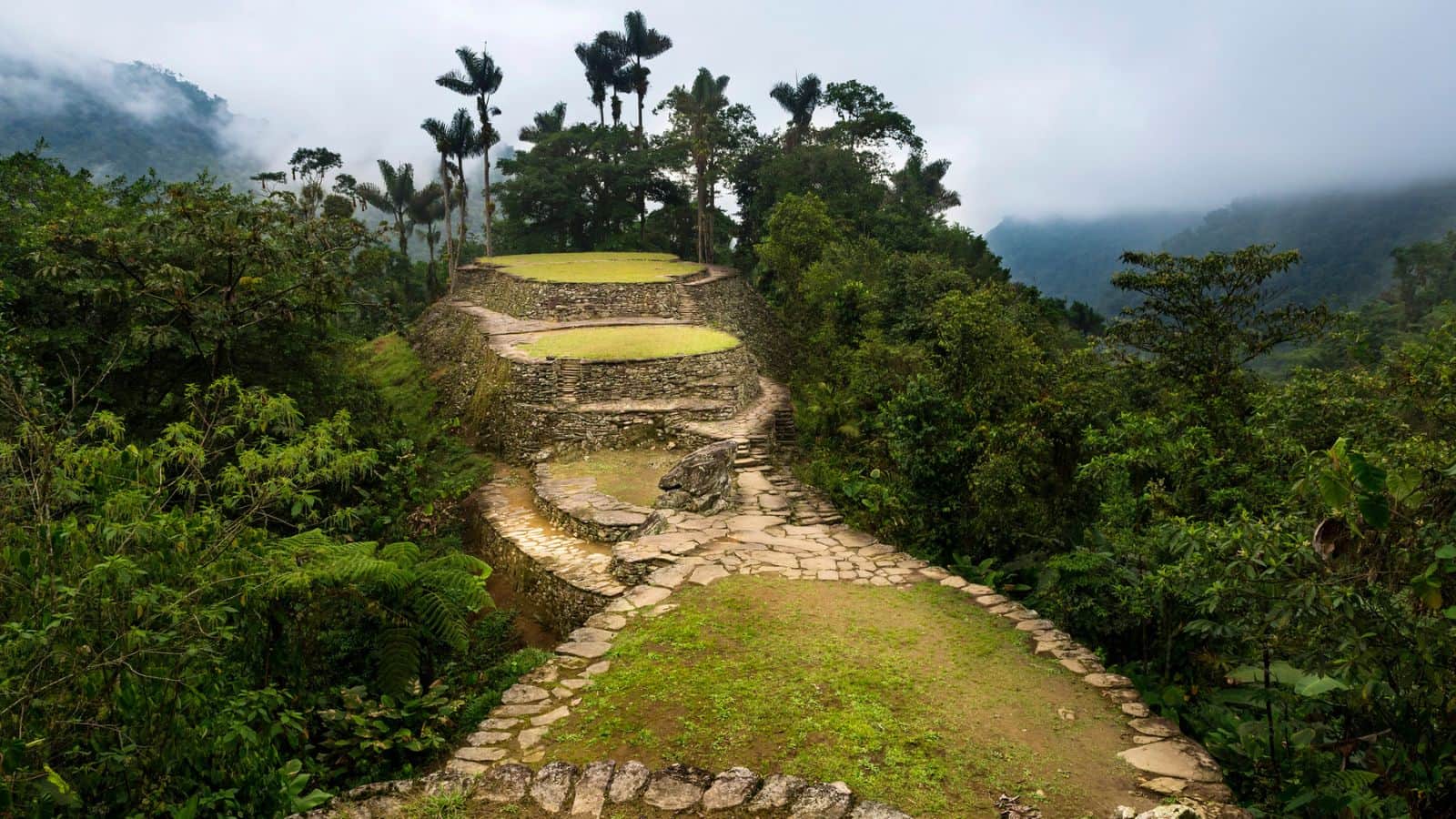 Ancient stone terraces and pathways surrounded by lush jungle and misty mountains.