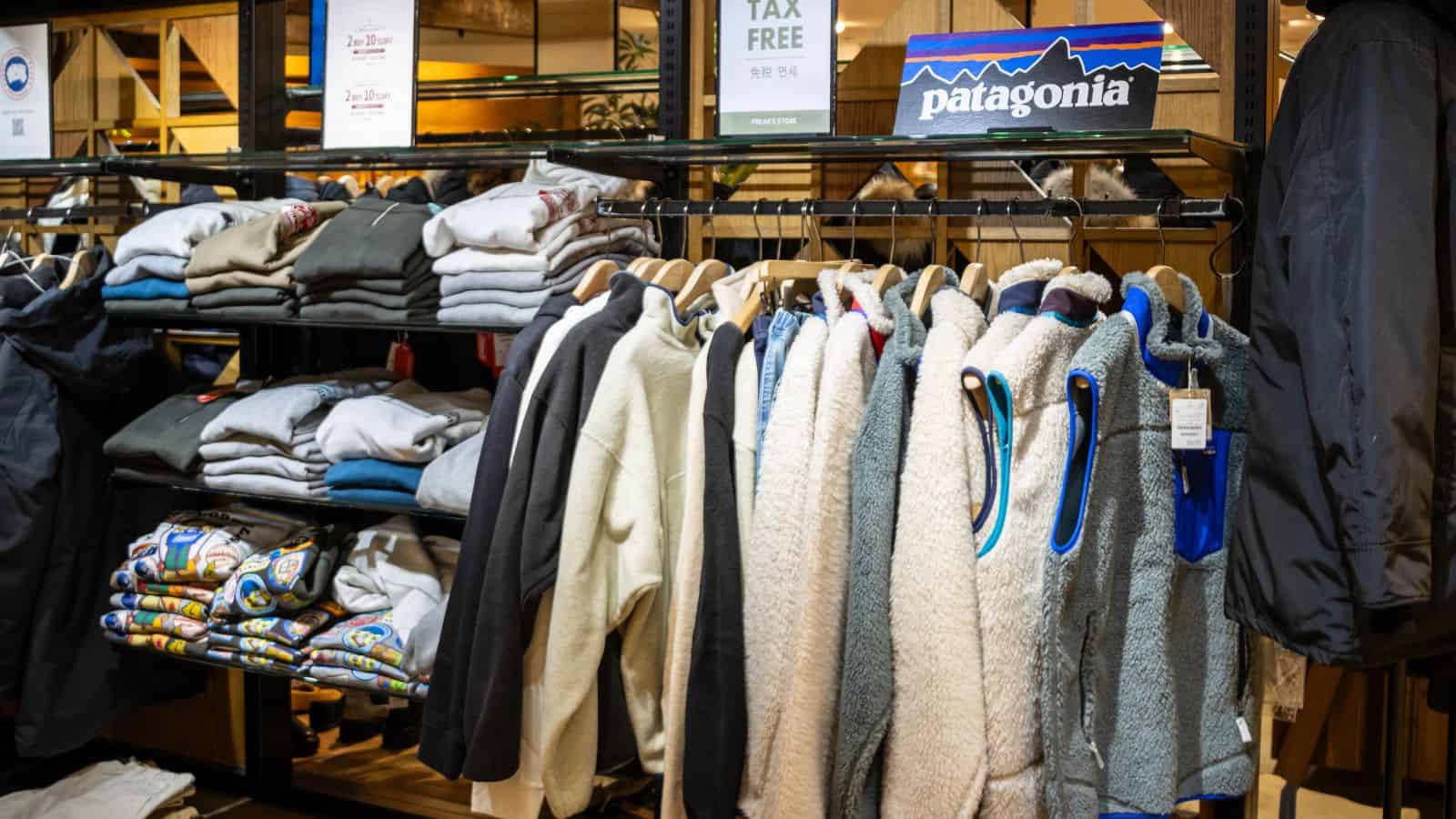 Clothing store display with Patagonia jackets and folded sweaters on shelves and racks.