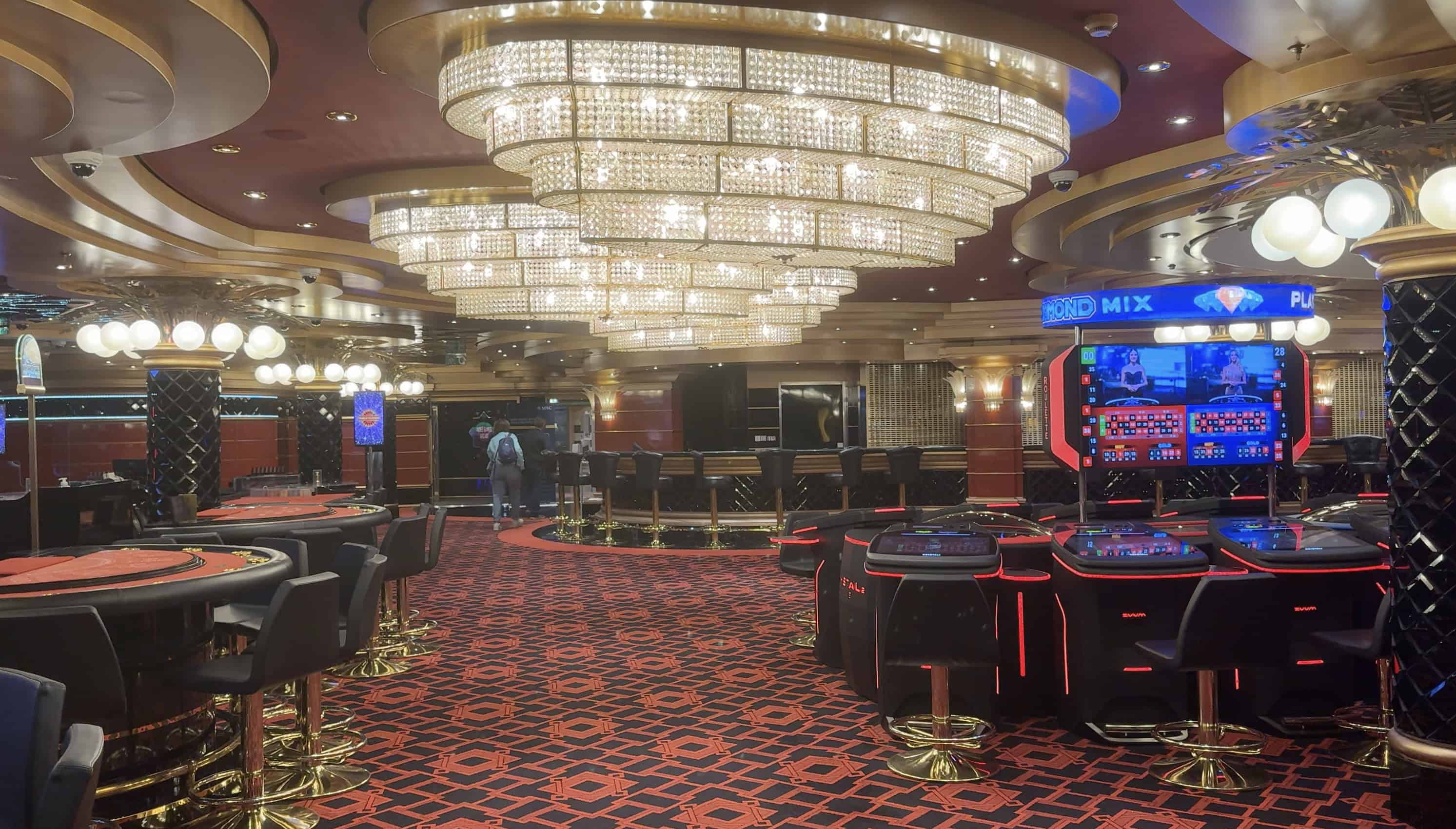 A luxurious casino interior aboard MSC Fantasia, featuring chandeliers, gaming tables, slot machines, and red patterned carpet—an elegant highlight mentioned in many 2025 Cruise Review articles.