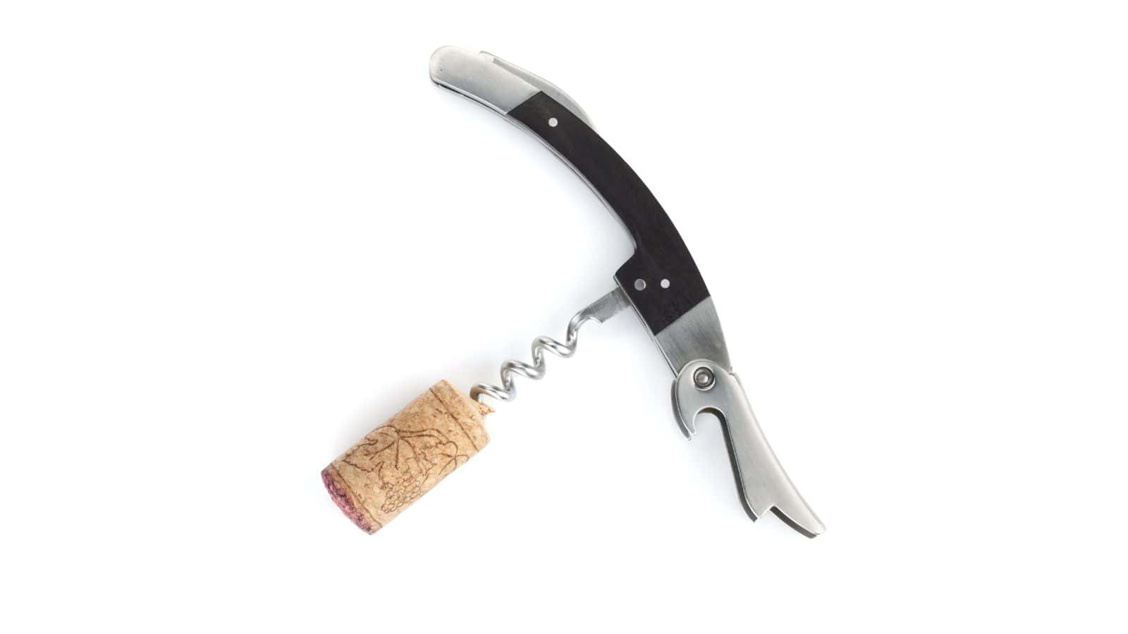 A corkscrew with a black handle and metal components, similar to those often found among confiscated items by TSA agents, is inserted into a wine cork, shown against a white background.