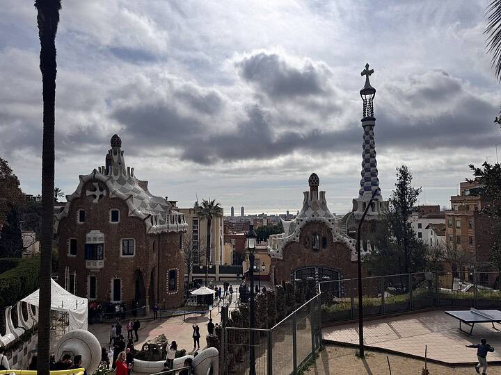 View of Park Güell's entrance buildings and cityscape under a cloudy sky in Barcelona, Spain—a perfect family stop on your MSC Fantasia Cruise 7-Day Itinerary.