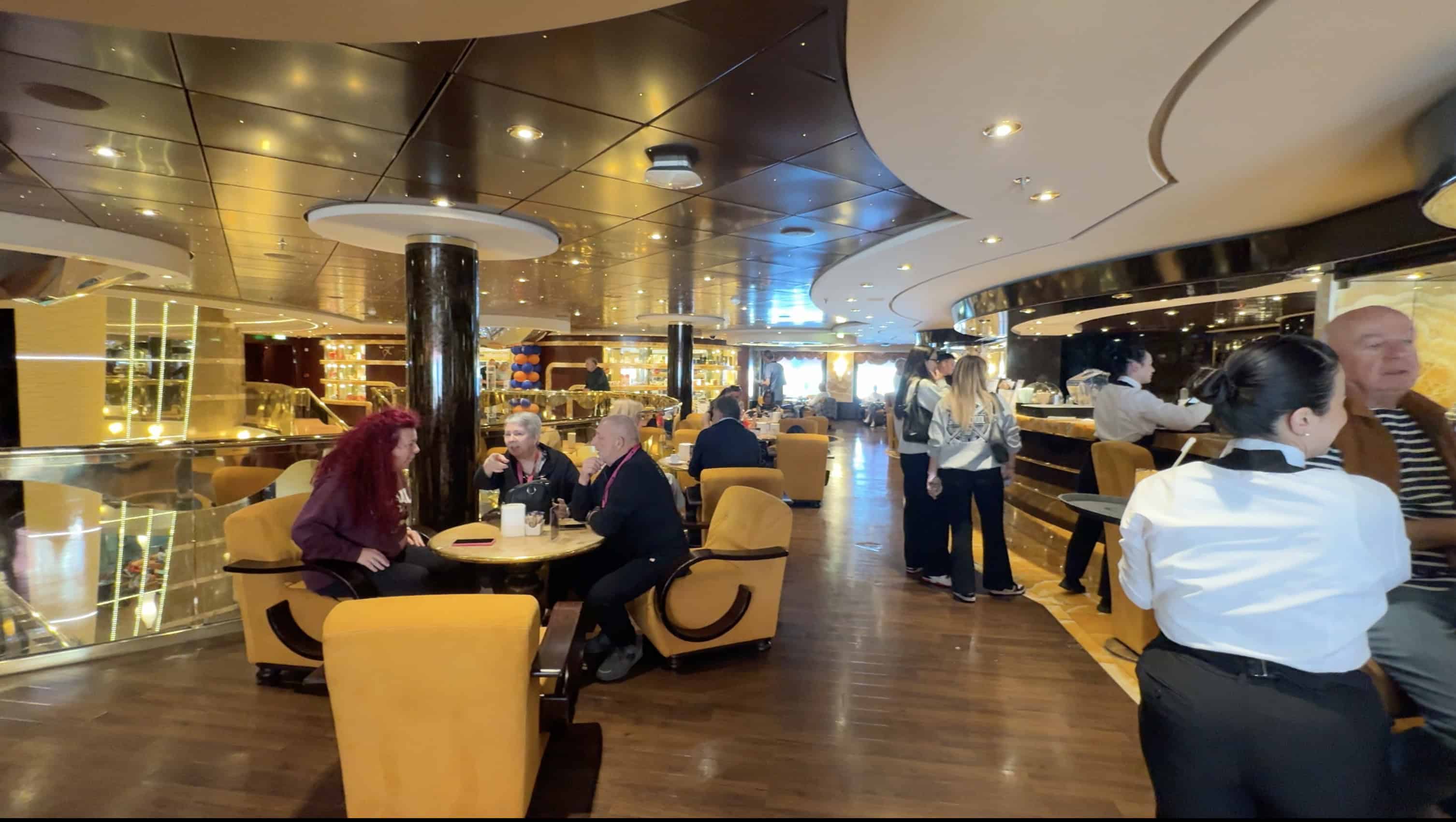 People sit and chat in a modern, stylish lounge with yellow chairs and a bar in the background, evoking the chic ambiance found in MSC Fantasia Dining areas.