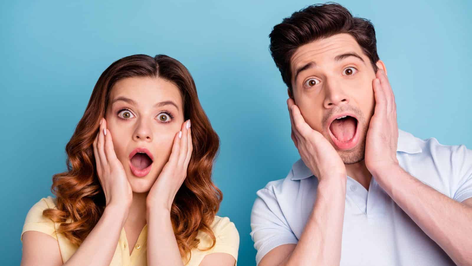 A surprised woman and man with hands on their faces, mouths open, against a blue background.