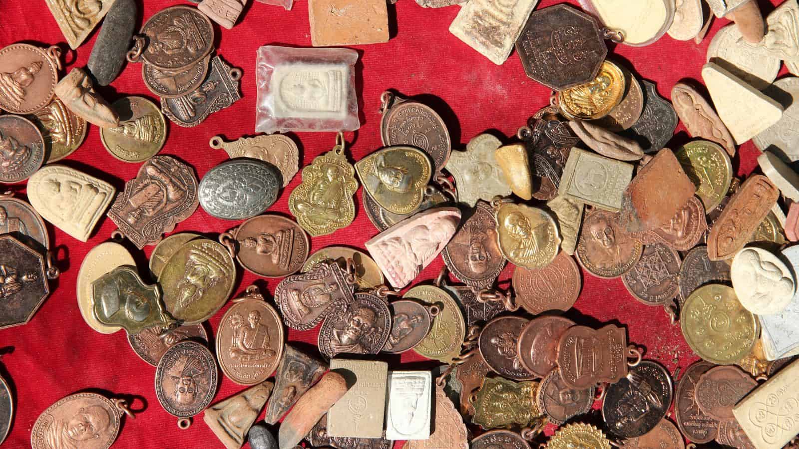 Assorted religious amulets and medallions displayed on a red cloth background.