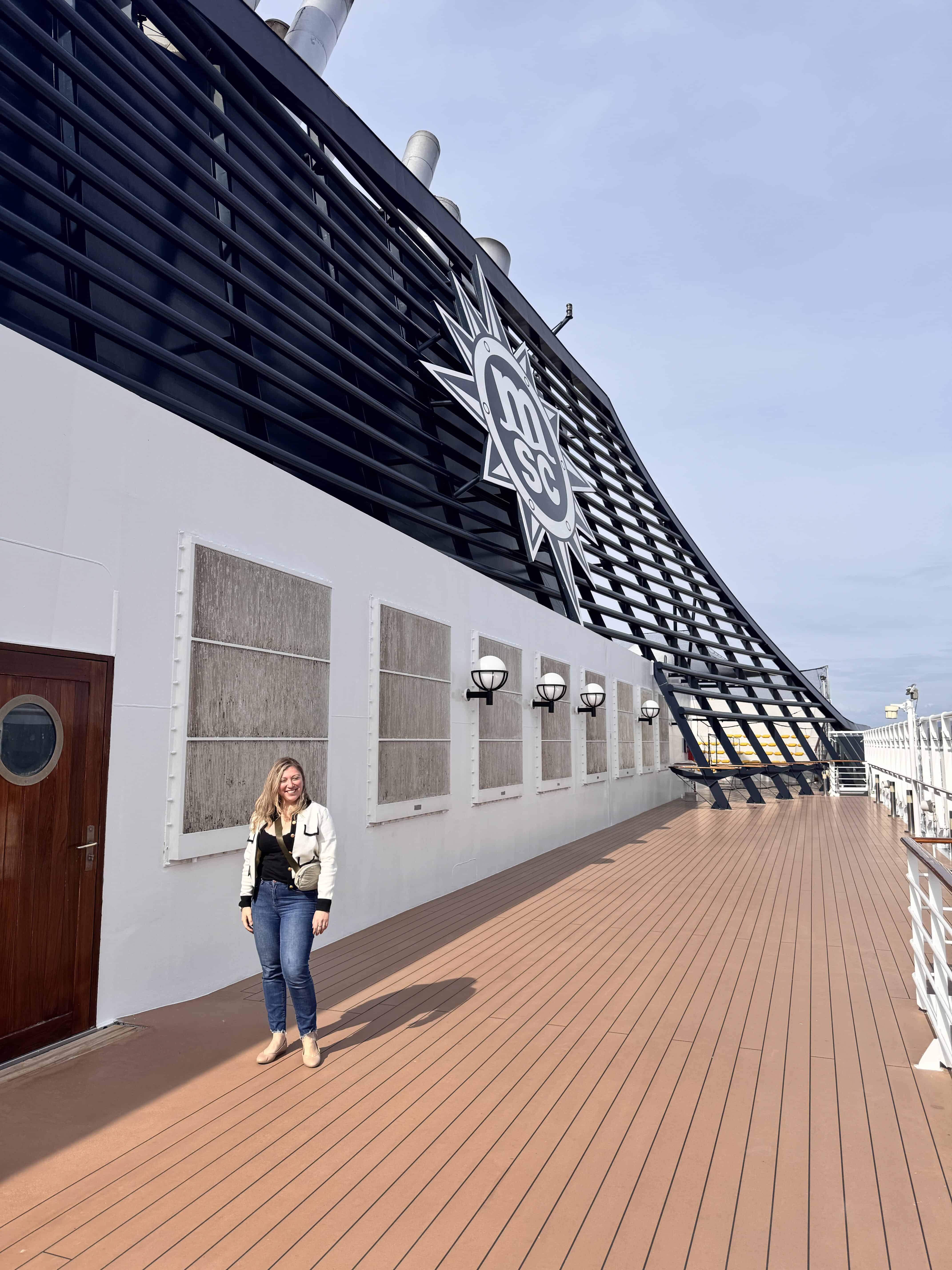A woman stands on the deck of MSC Fantasia under a blue sky, capturing a perfect moment for a 2025 cruise review.