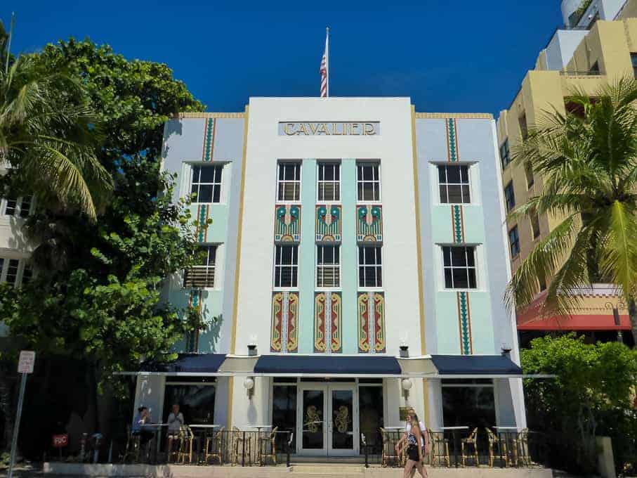 Art Deco Cavalier Hotel with colorful vertical accents, palm trees, and a clear blue sky in Miami Beach.