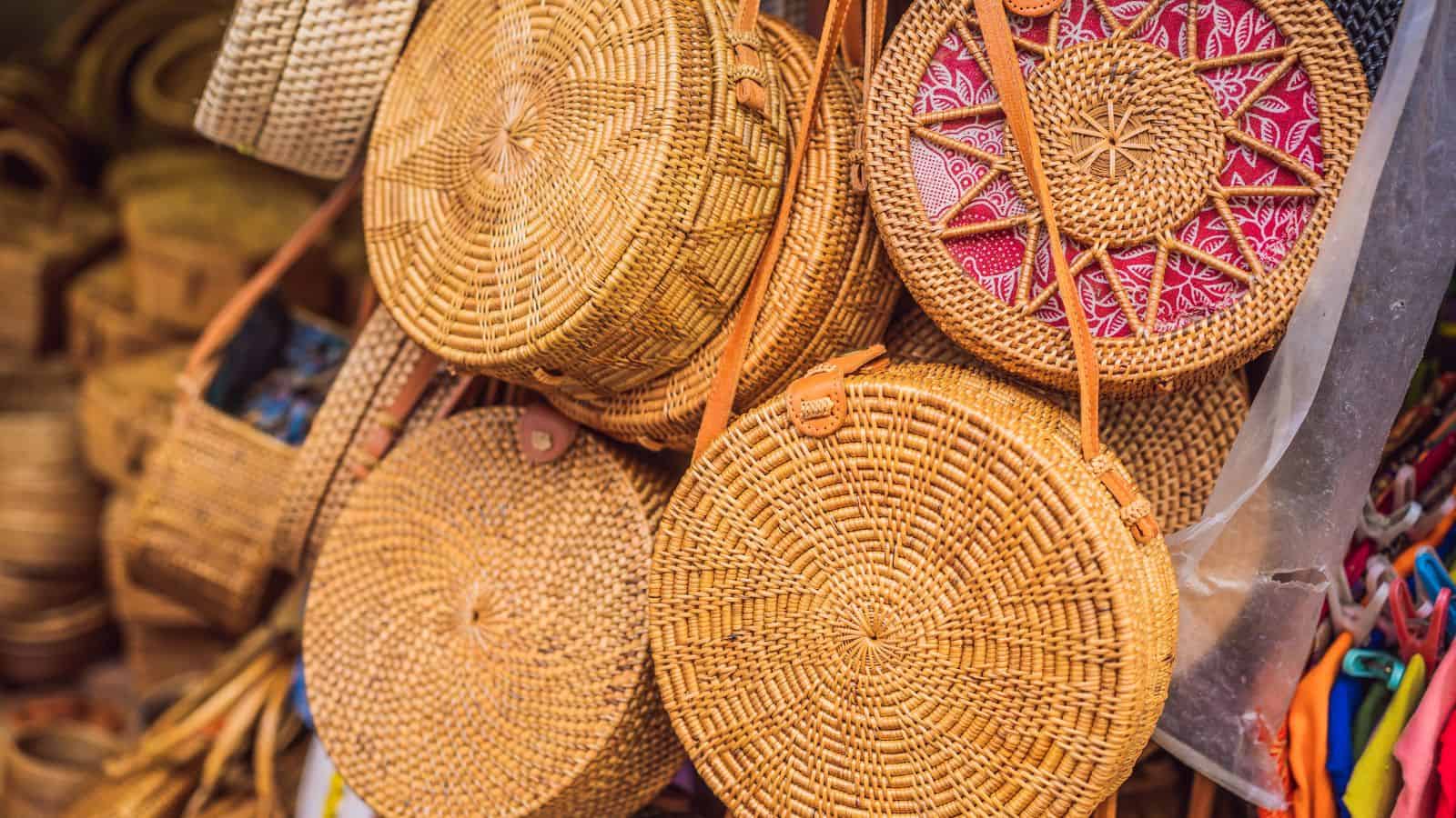 Round woven rattan bags with leather straps on display at a market stall.