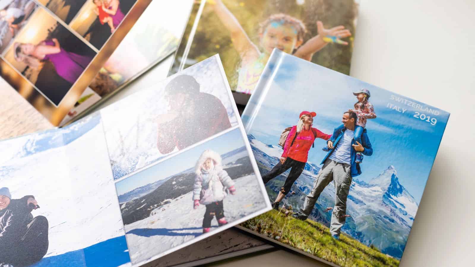 Photo books with family travel pictures open on a white table, one labeled "Switzerland Italy 2019.
