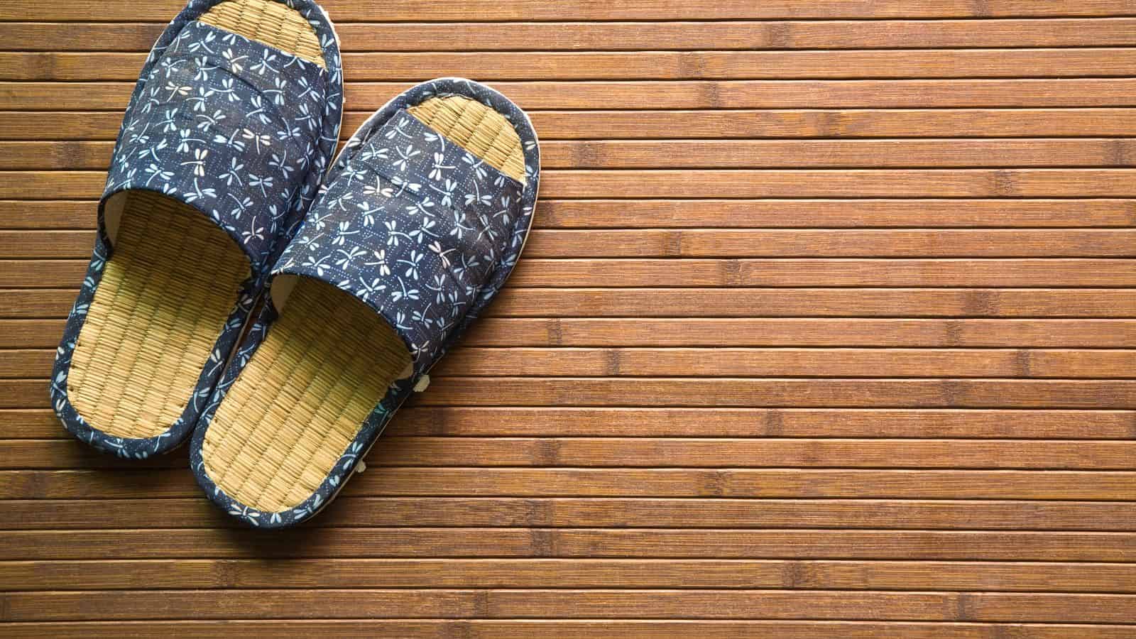 Blue patterned slippers on a bamboo mat, positioned to the left with empty space on the right.