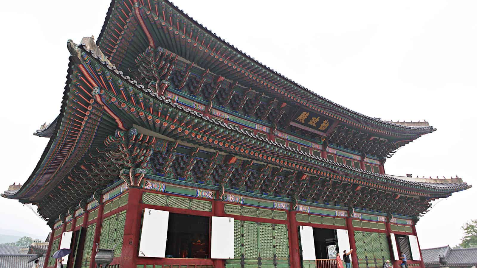 A traditional Korean palace building with ornate green, red, and gold details and curved rooftops.