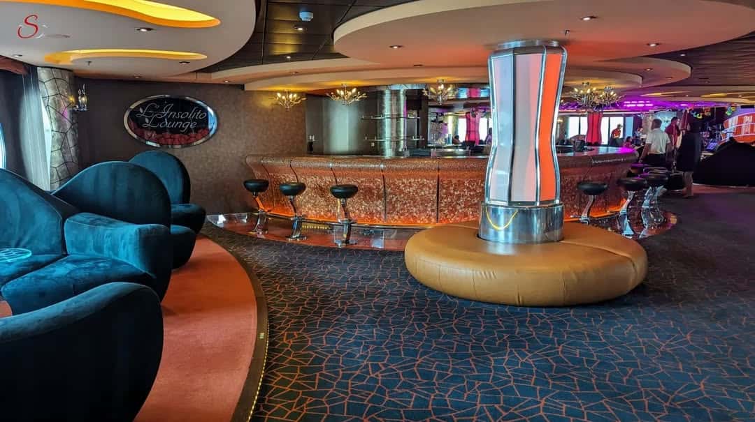 A modern, colorful lounge bar with velvet seating, orange accents, and unique lighting fixtures—perfect for relaxing after an MSC Fantasia Dining experience.
