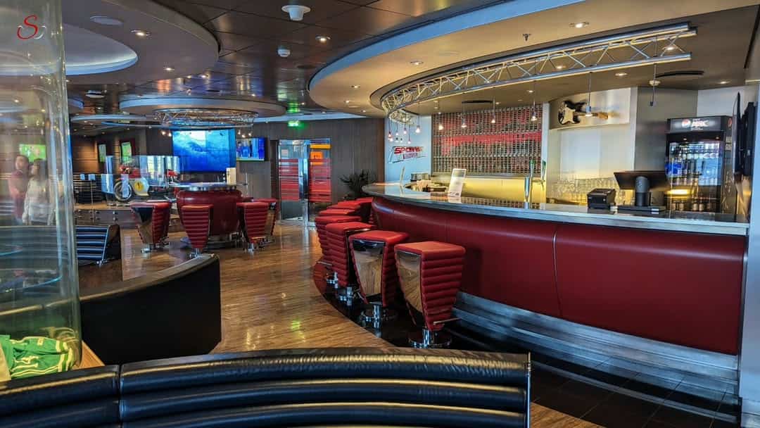 A modern lounge inspired by MSC Fantasia Dining, featuring red bar stools, a curved bar, and seating areas with ambient lighting.