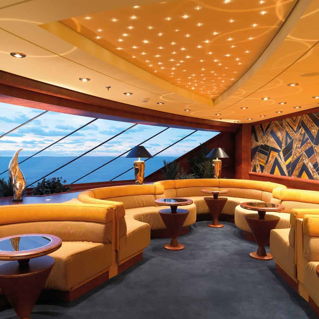 Luxurious lounge with curved yellow sofas, star-like ceiling lights, and ocean view through large windows—perfect for relaxing before indulging in MSC Fantasia Dining.