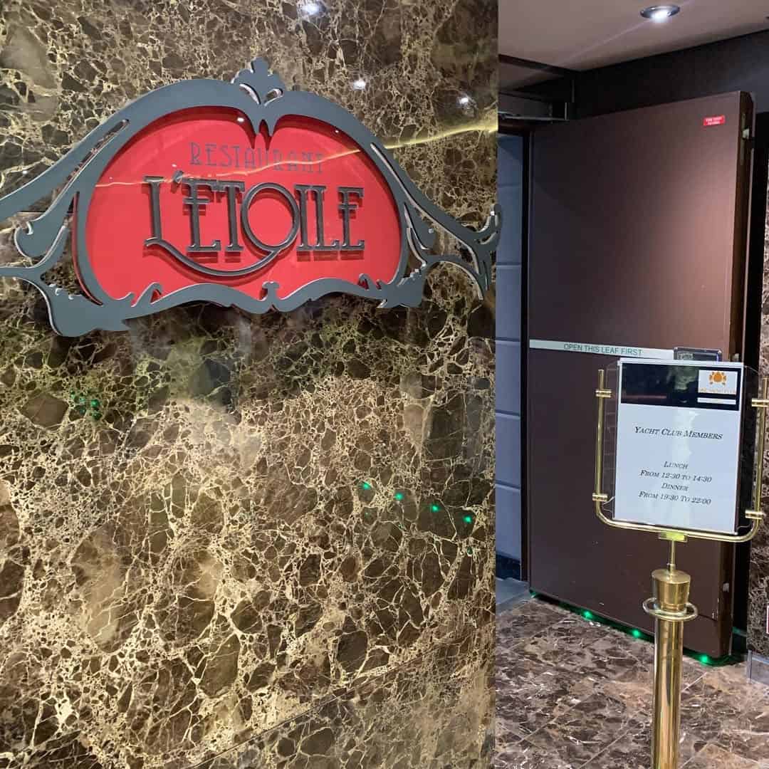 Sign for "Restaurant L'Etoile" on a marble wall, with a menu stand and dark doors nearby, showcasing the refined ambiance typical of MSC Fantasia Dining.