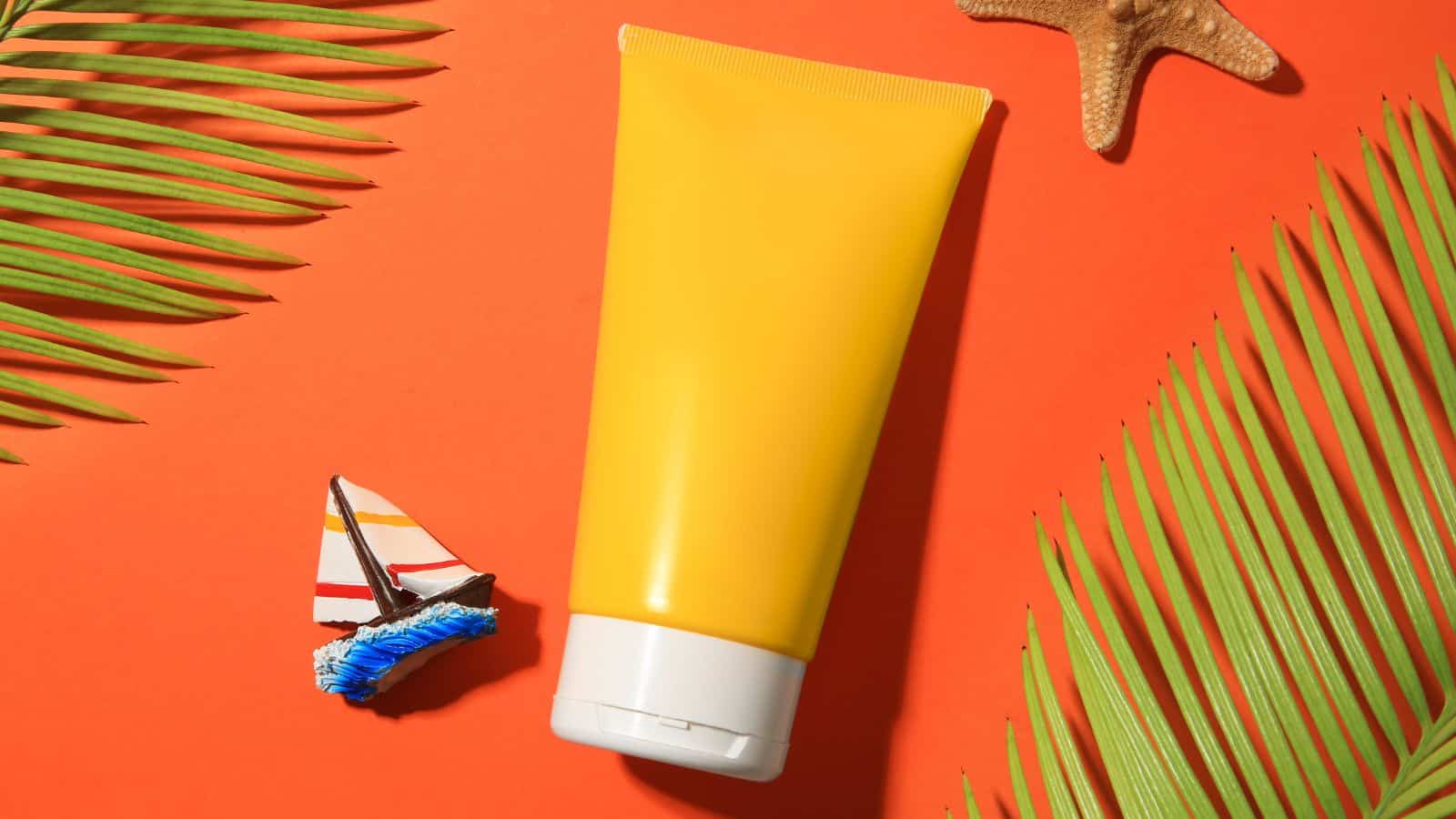 A yellow tube with a white cap is placed on an orange surface, surrounded by palm leaves, a starfish, and a small toy sailboat&mdash;some of the surprising items TSA agents might confiscate during travel.