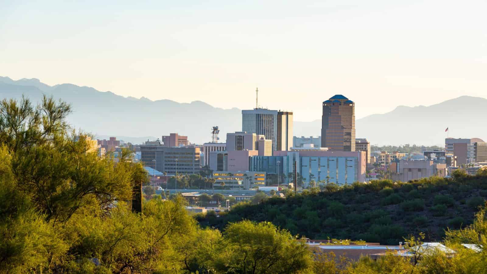 Tucson city skyline with mountains in the background and trees in the foreground under a clear sky, highlighting one of the U.S. cities facing concerns about water shortage.
