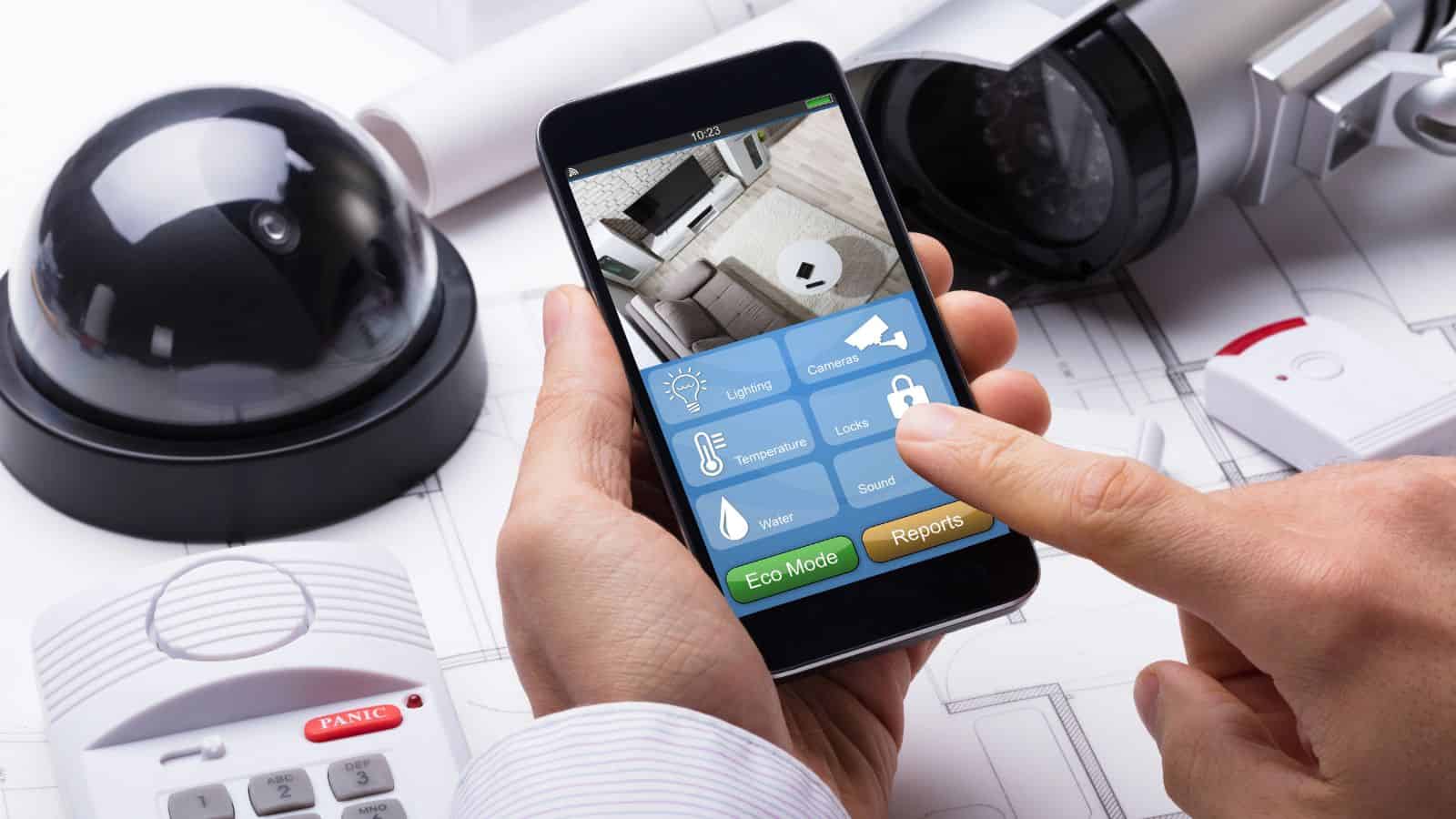 Person using a smartphone to control security cameras and home automation, surrounded by security devices.