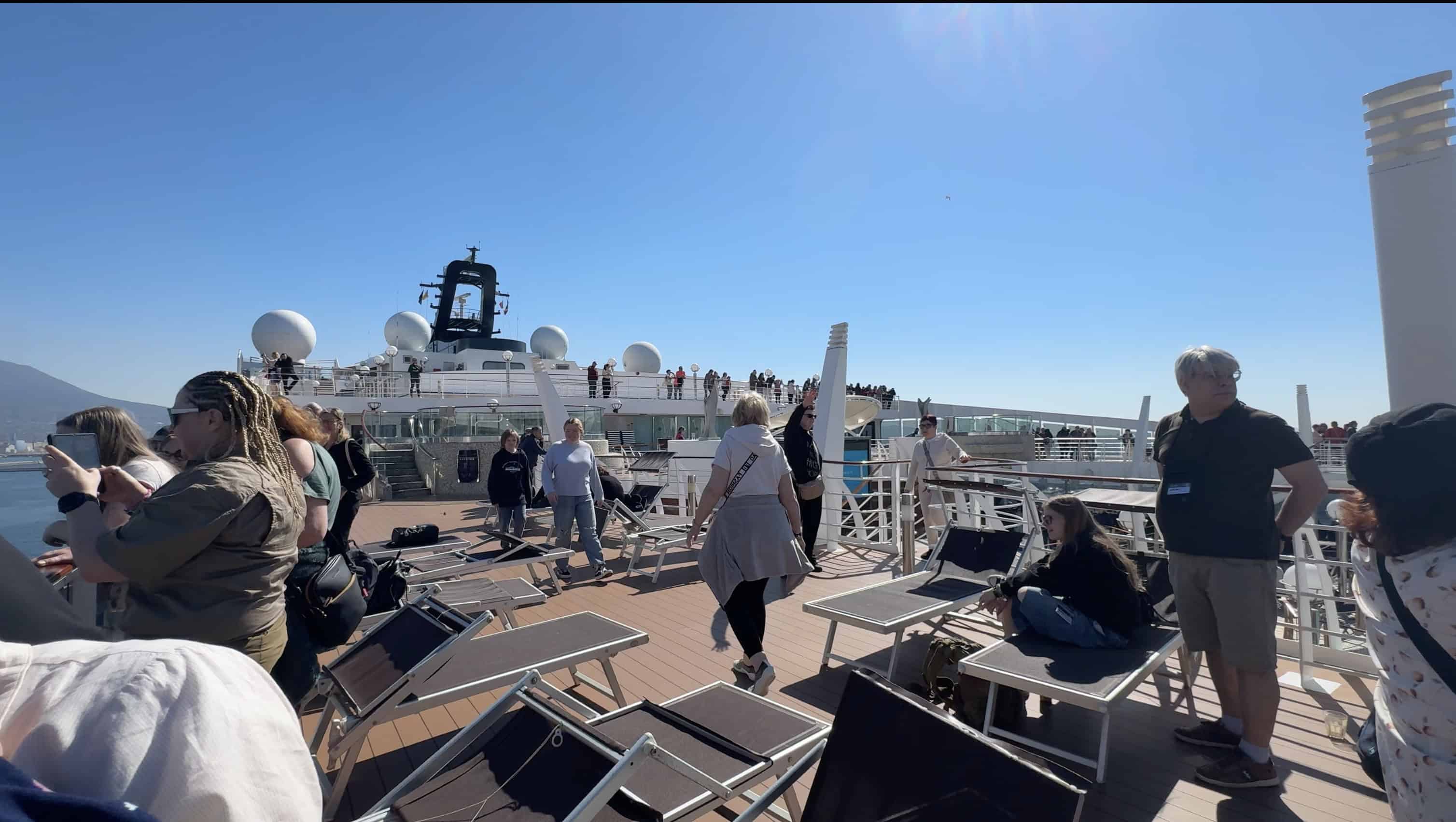 Families enjoying a sunny day, walking and relaxing on the deck of an MSC Mediterranean cruise—perfect for family travel under a clear blue sky.