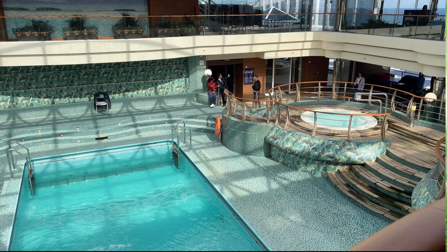 Indoor pool area with a hot tub, mosaic tile decor, curved steps, and sunlight streaming through the glass ceiling—perfect for a relaxing Family Cruise Experience aboard MSC Fantasia Cruise.