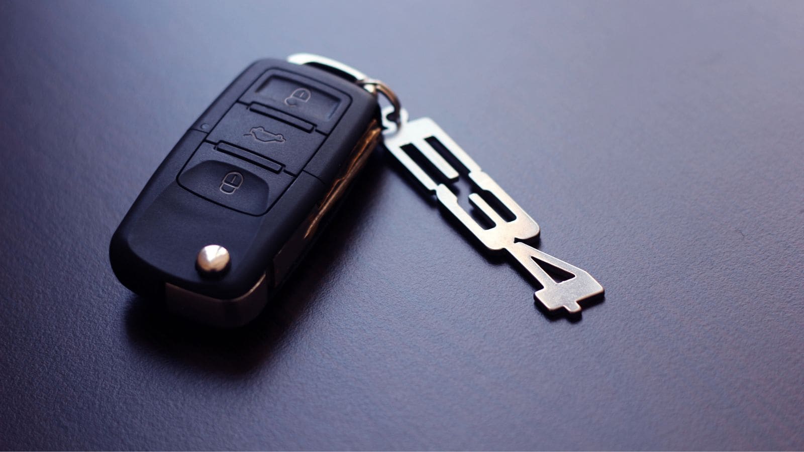 Car key fob with a metal keychain labeled "E34" on a dark surface.
