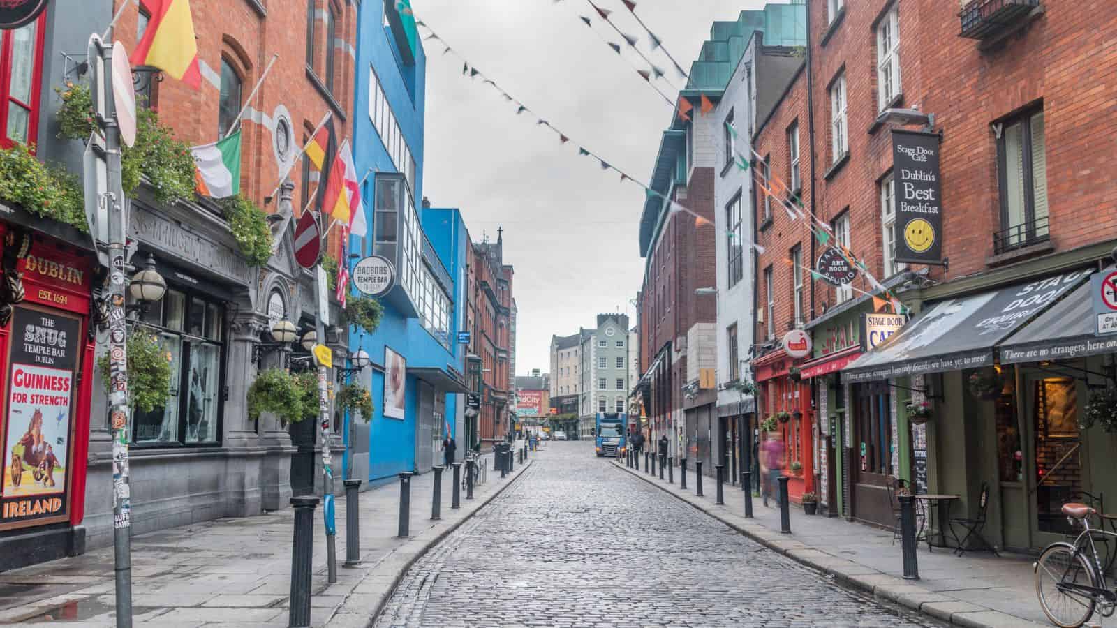 A cobblestone street lined with colorful buildings and flags in Dublin, Ireland.