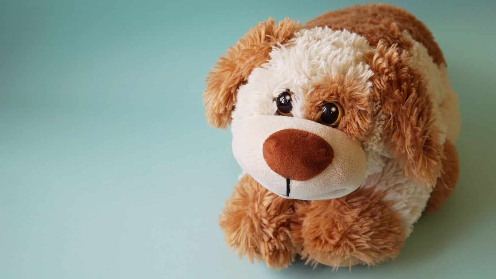 Plush brown and white stuffed dog toy on a light blue background—an adorable travel essential for flying with kids or comforting little ones under 5.