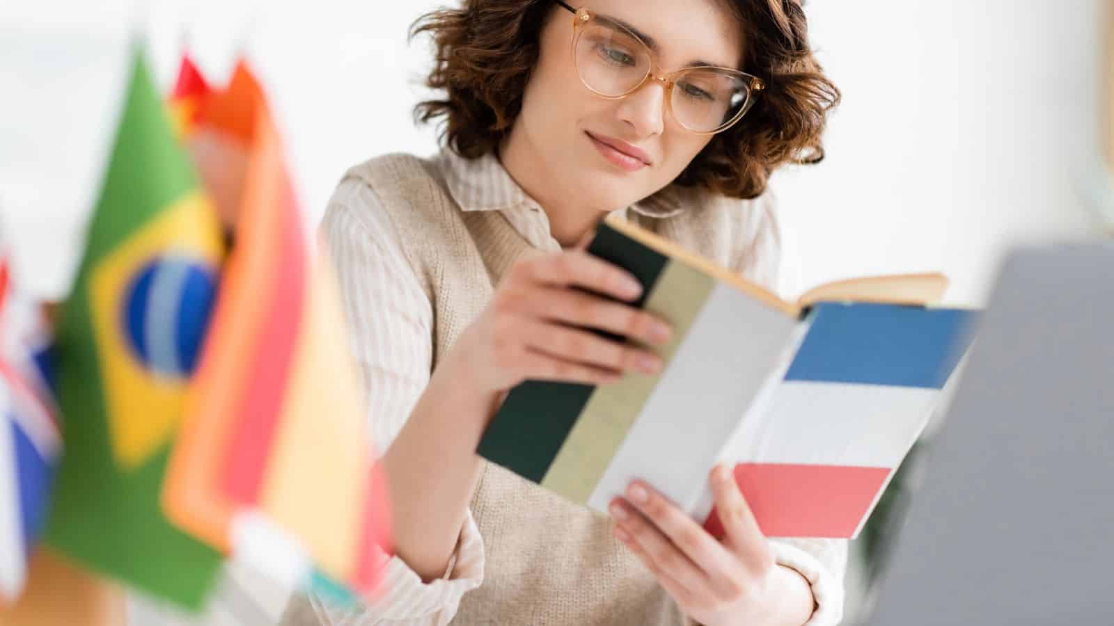 A woman reads a book with a French flag cover, surrounded by various international flags.