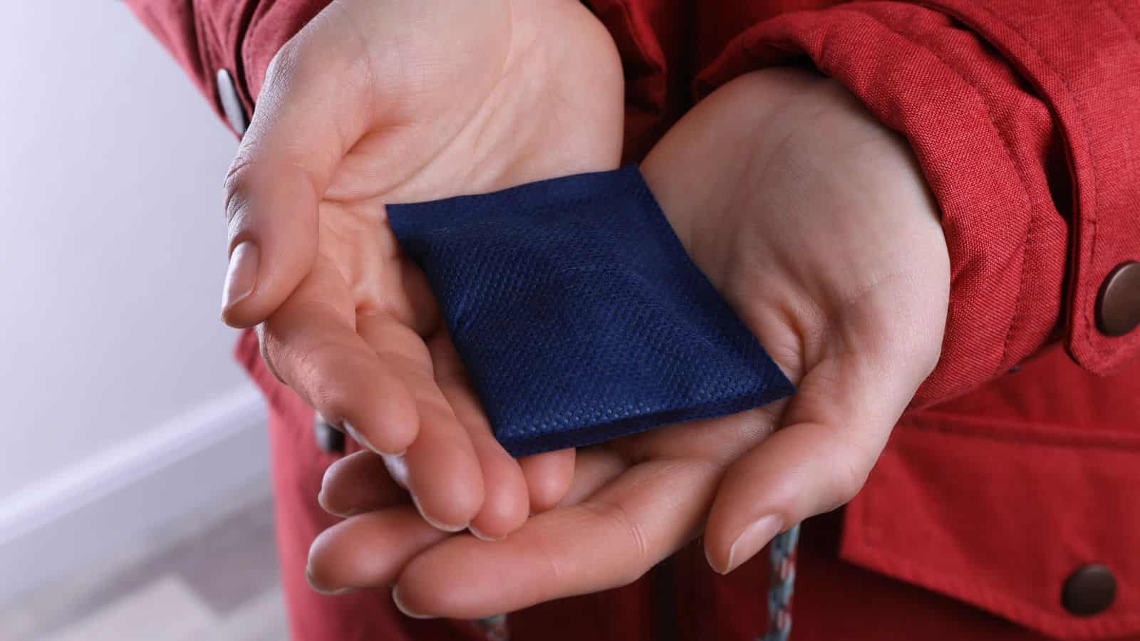 Person in a red coat holding a small blue fabric pouch in their open hands.