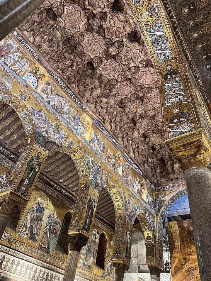 Ornate vaulted ceiling and arches with detailed mosaics and religious artwork in a historic building.