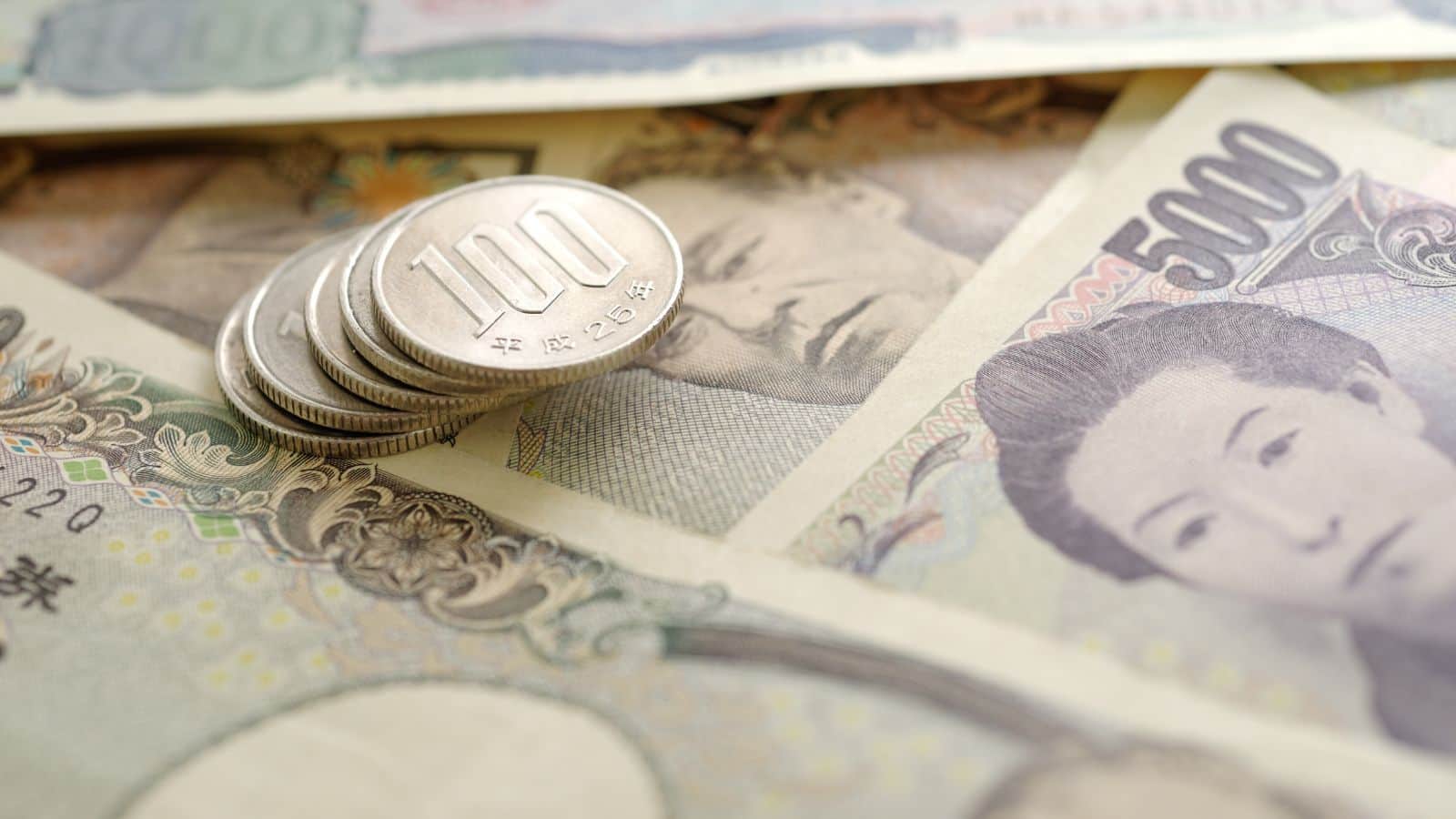 Japanese yen coins and banknotes, including 100 yen coins and 5,000 yen bills, spread on a surface.