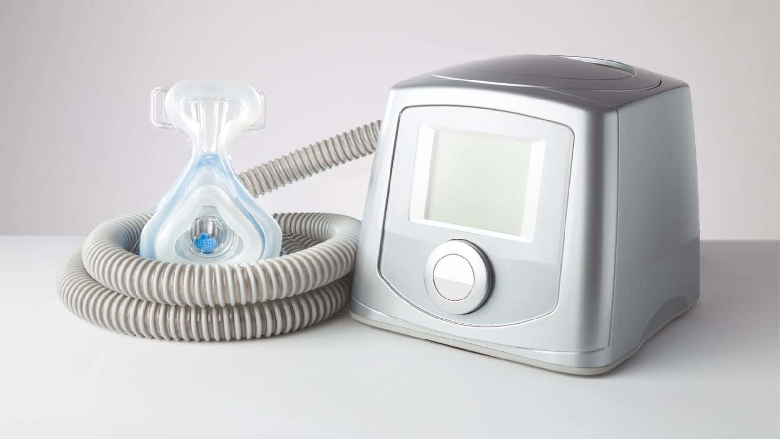 A CPAP machine with a hose and face mask, used for sleep apnea therapy, on a white surface—one of the things that get you stopped by airport security 2025.