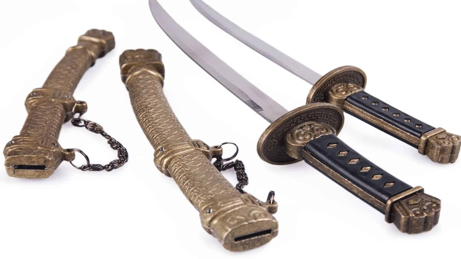 Two ornate swords with black handles and gold sheaths, displayed on a white background.