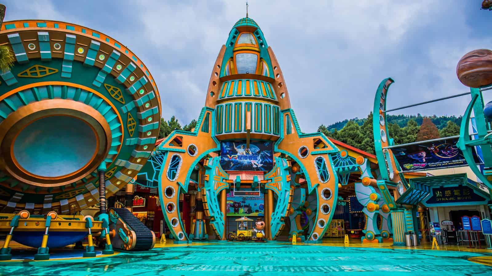 Colorful, futuristic rocket-shaped building at an amusement park, with vibrant orange and teal details.
