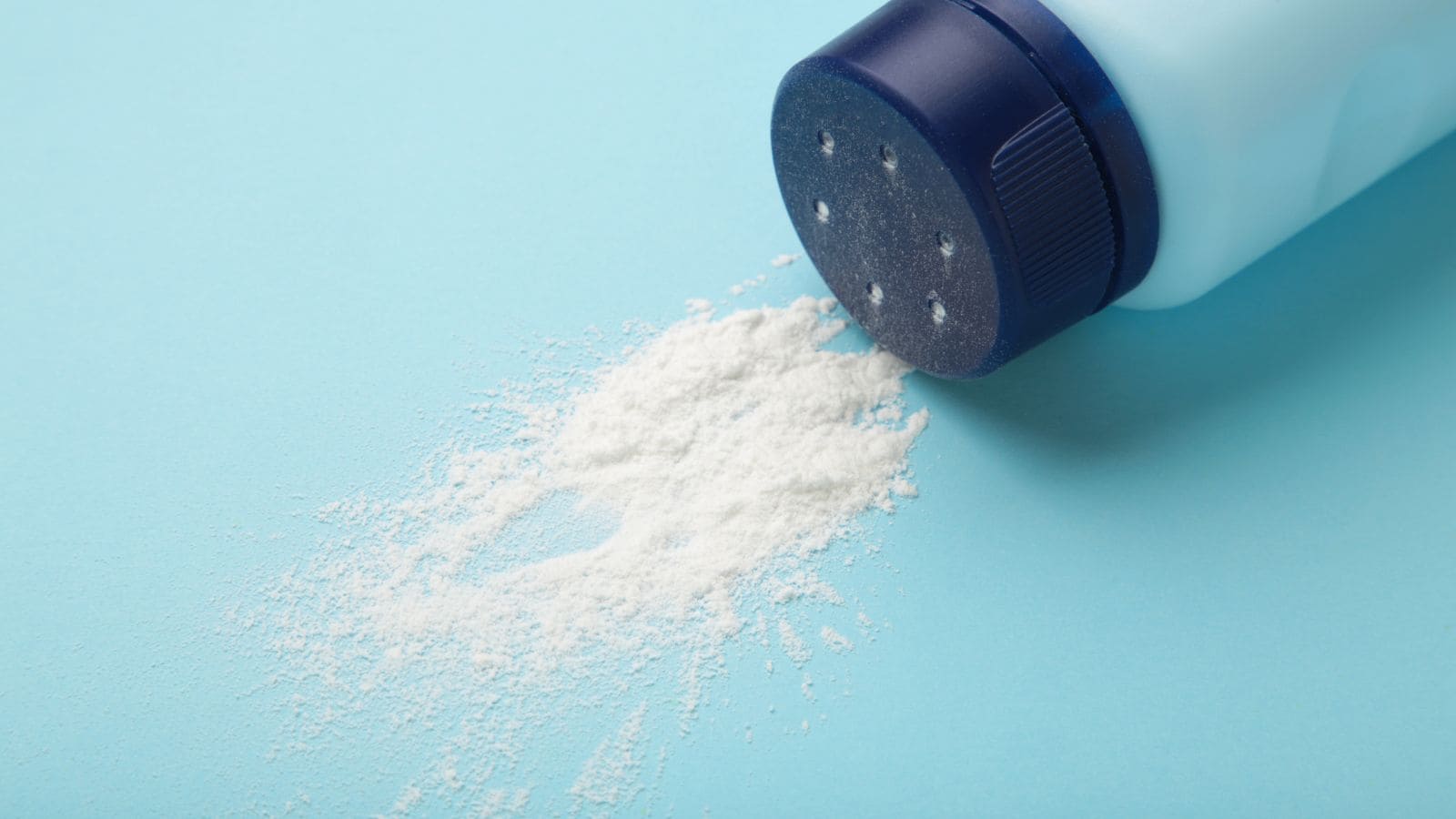 Open bottle of white powder spilling onto a light blue surface.