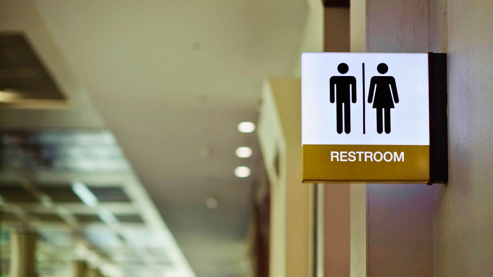 A restroom sign showing male and female symbols mounted on a wall in a public building.