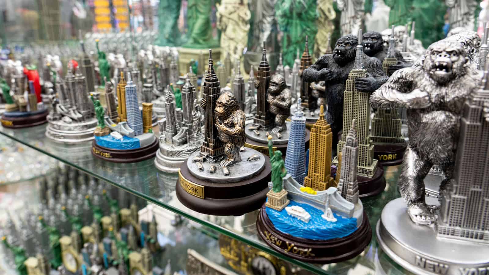 Metal King Kong and New York City skyline souvenirs displayed on glass shelves in a gift shop—perfect reminders of your trip and clever options if you're looking for ways to save money while you’re already on a cruise.