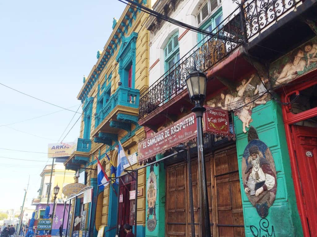 Colorful buildings with balconies and murals line a lively street in La Boca, one of the top things to do in Buenos Aires, Argentina.