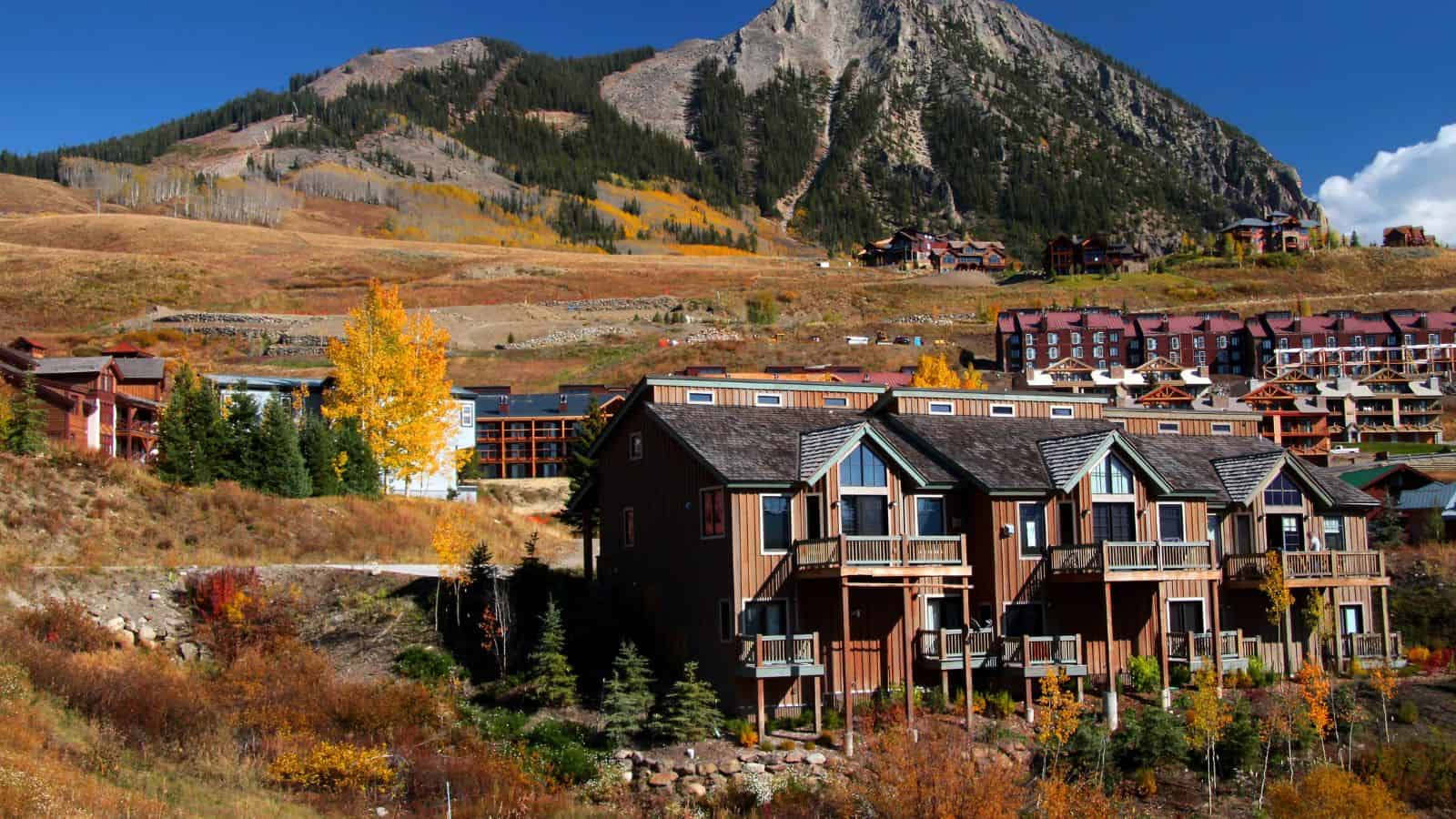 A group of houses in a valley with mountains in the background, perfect for weekend getaways and those seeking hidden destinations.