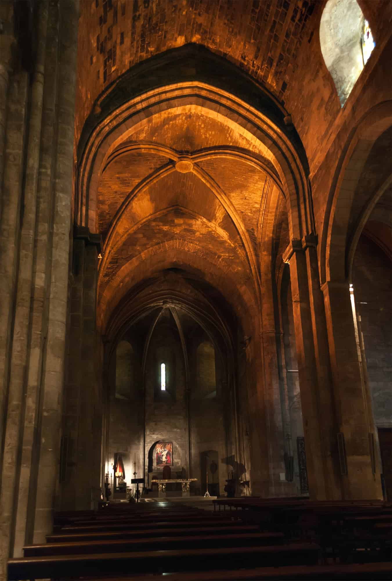 Dimly lit Gothic church interior with vaulted ceilings, arches, and an altar at the far end—an atmospheric highlight on any Marseille, France One Day Itinerary.