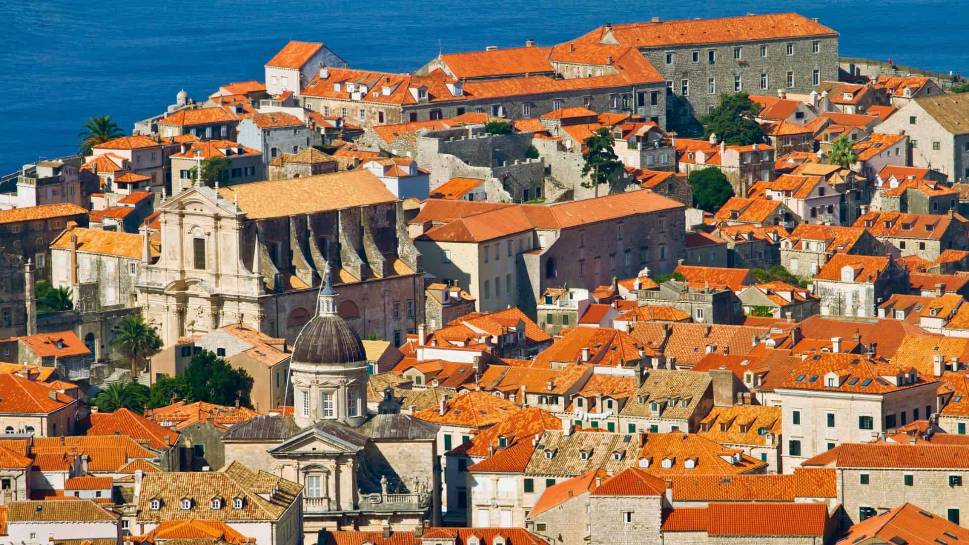 Aerial view of Dubrovnik&rsquo;s old town with orange rooftops and historic buildings by the blue sea.