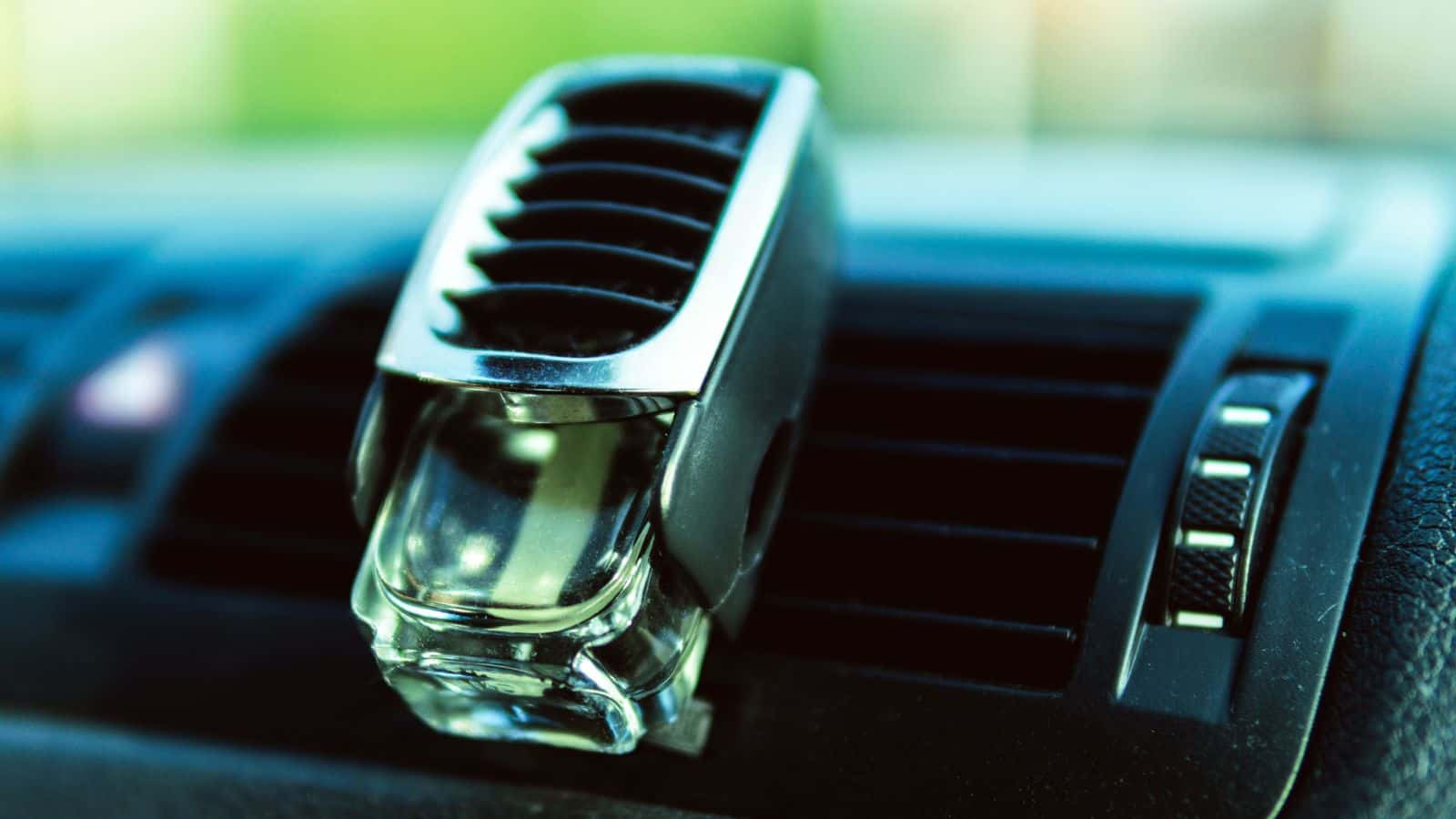 Close-up of a car air freshener clipped onto a black dashboard air vent.