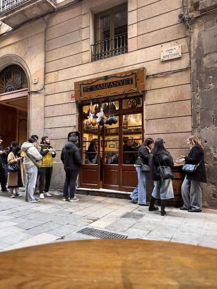 A group of people standing outside a building, discussing where to eat and exploring the fresh food options at Barcelona markets.