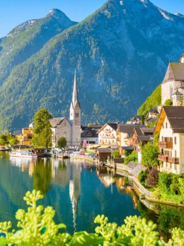 Colorful lakeside village with mountains in the background and a church steeple rising above the houses.