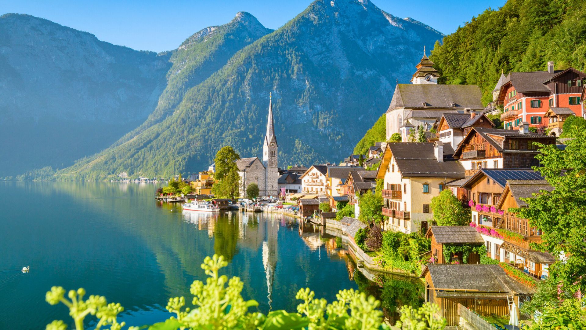 Colorful lakeside village with mountains in the background and a church steeple rising above the houses.