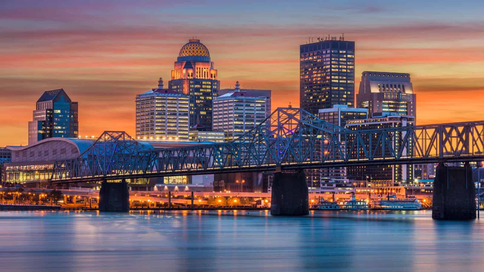 City skyline with a bridge over water at sunset, buildings lit up against a colorful sky—an ideal backdrop for celebrating unusual holidays in one of the top states.