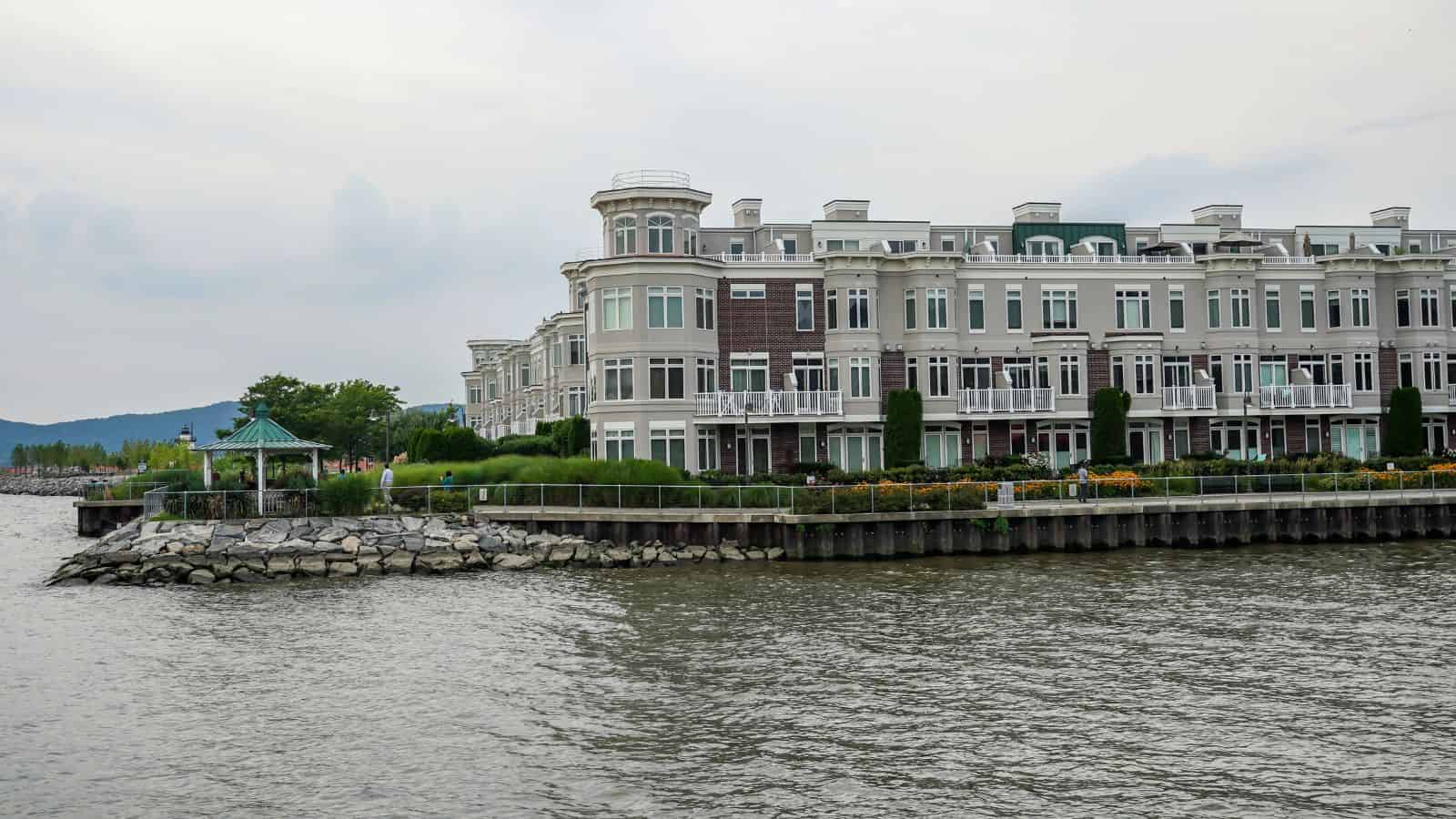 Waterside view of modern condos with a gazebo and landscaped greenery along the shoreline.